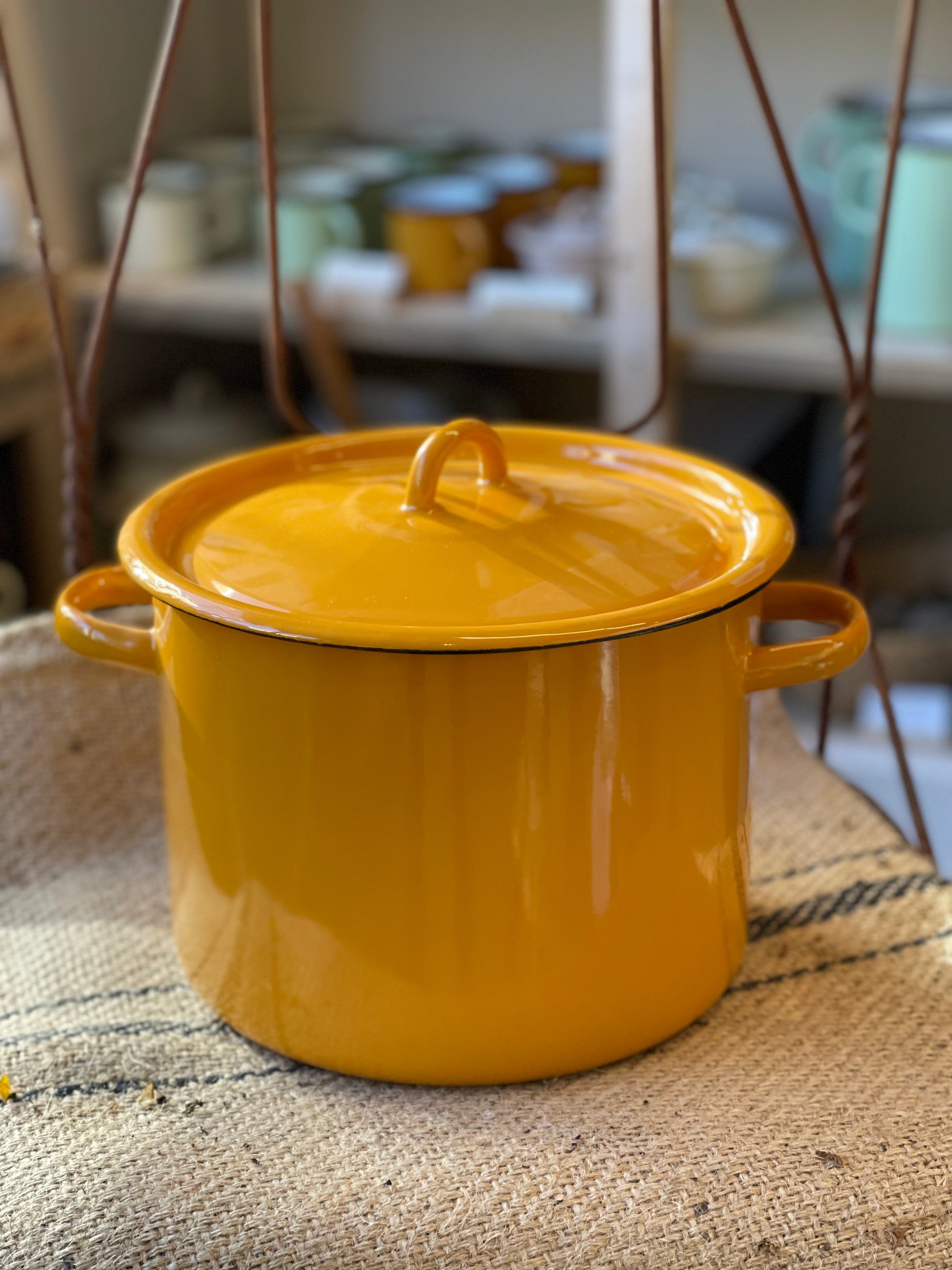 Yellow enameled pot with lid on a textured surface