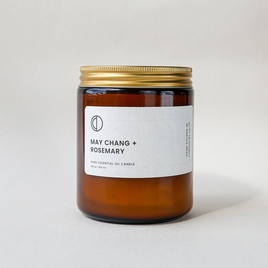 Amber candle jar with gold lid and white label on a light gray background