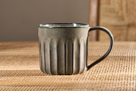 nkuku pewter ceramic mug with a textured design on a woven surface