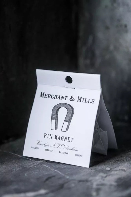 Pin magnet packaging with 'Merchant & Mills' label on a dark background