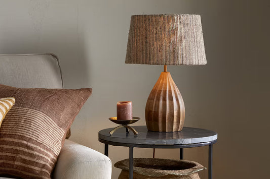 Wooden lamp on a side table next to a sofa with pillows