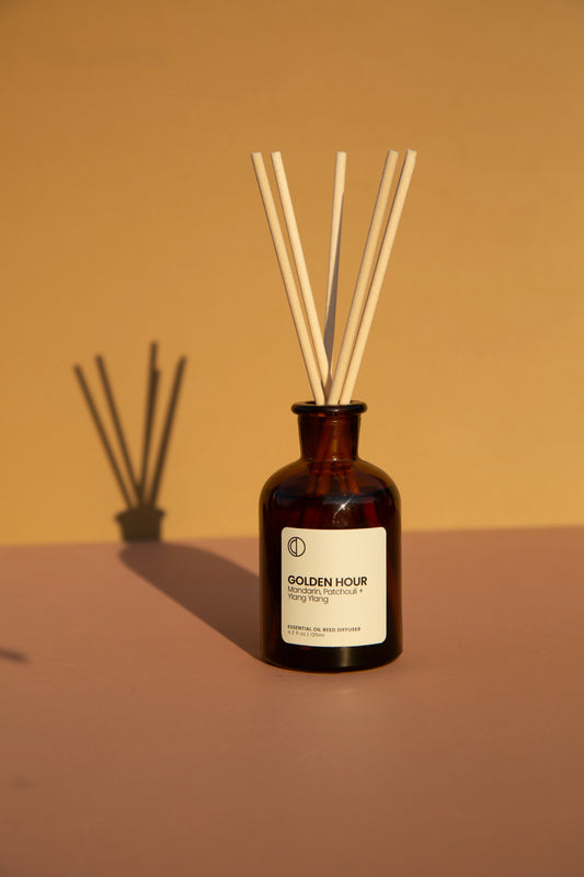 OCTO Golden Hour Natural fragrances of Mandarin Patchouli and Ylang Ylang Reed Diffuser Brown diffuser bottle with wooden sticks on a brown background
