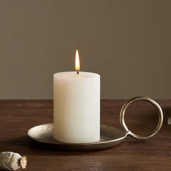 nkuku Candle burning on a wooden surface with a vase and book in the background