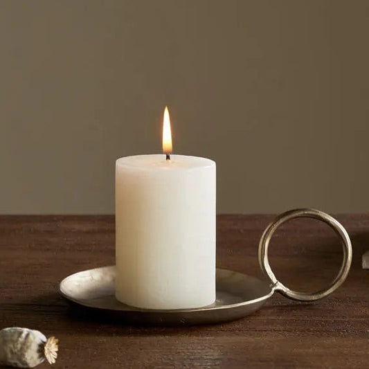 nkuku Candle burning on a wooden surface with a vase and book in the background