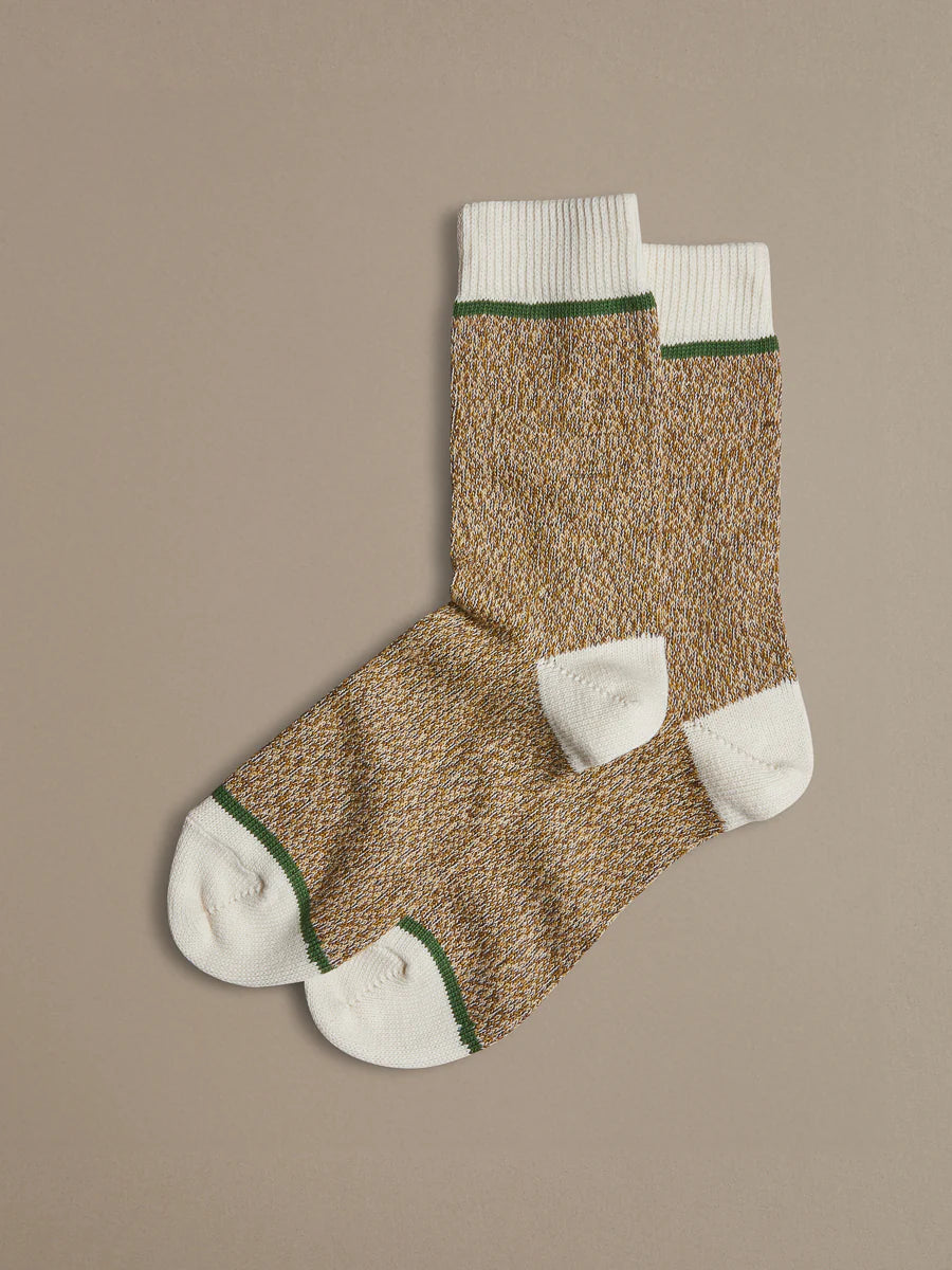 Pair of brown Rove socks with white toes and green trim on a beige background