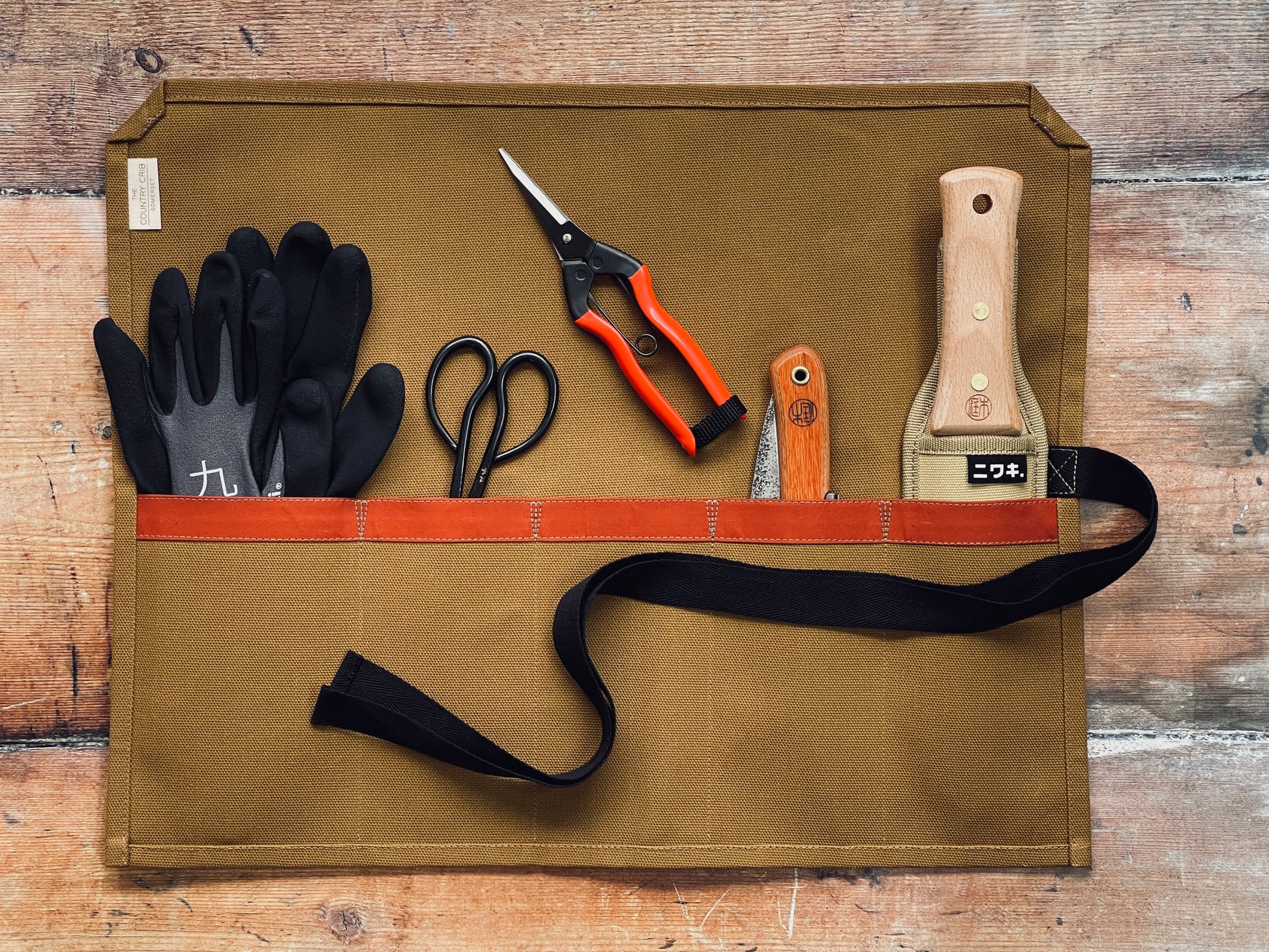 Mustard organic cotton canvas tool roll made by The Country Crib containing gardening tools on a wooden surface