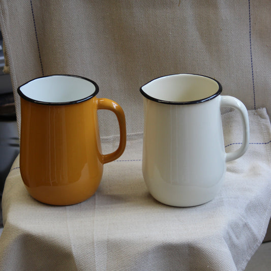 Two jugs, one yellow and one white, on a textured surface.