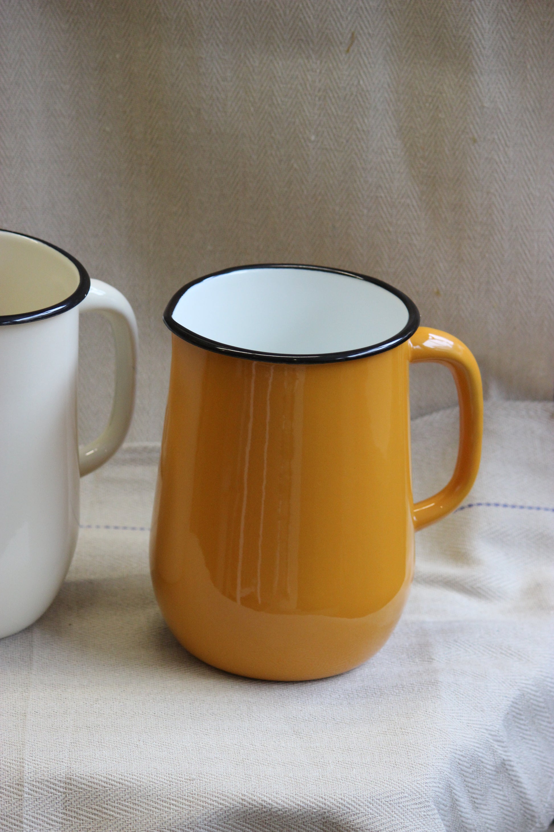 Yellow and white mugs with black rims on a textured fabric background