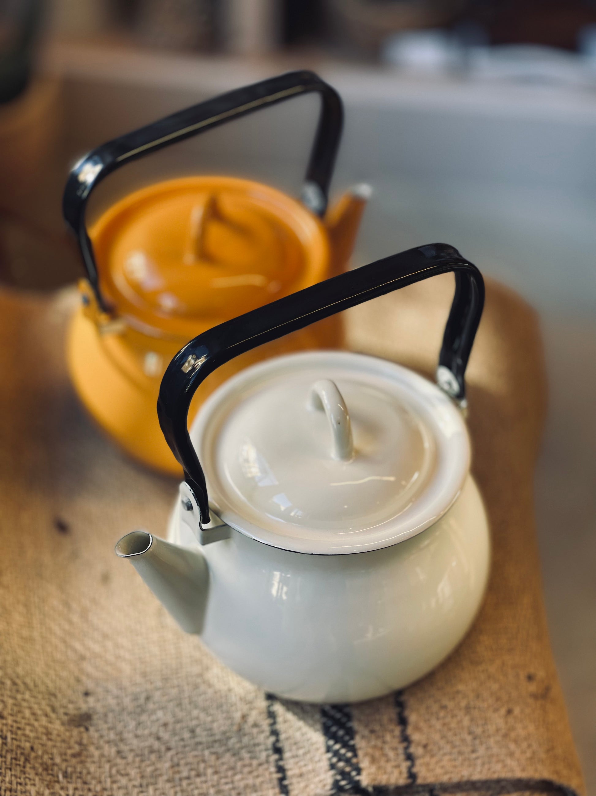 White kettle with black handle on a woven mat