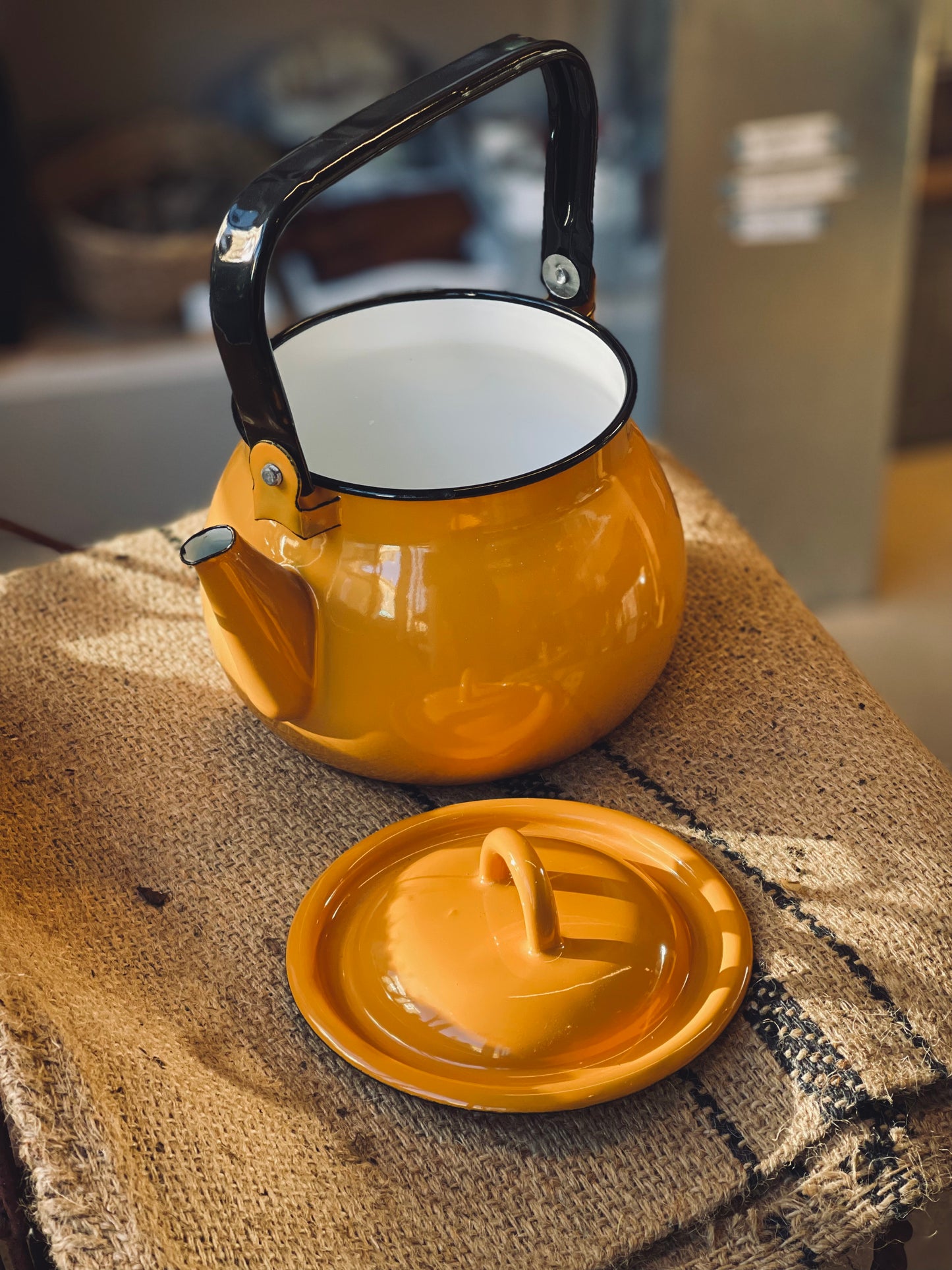 Yellow kettel with black handle on a textured surface