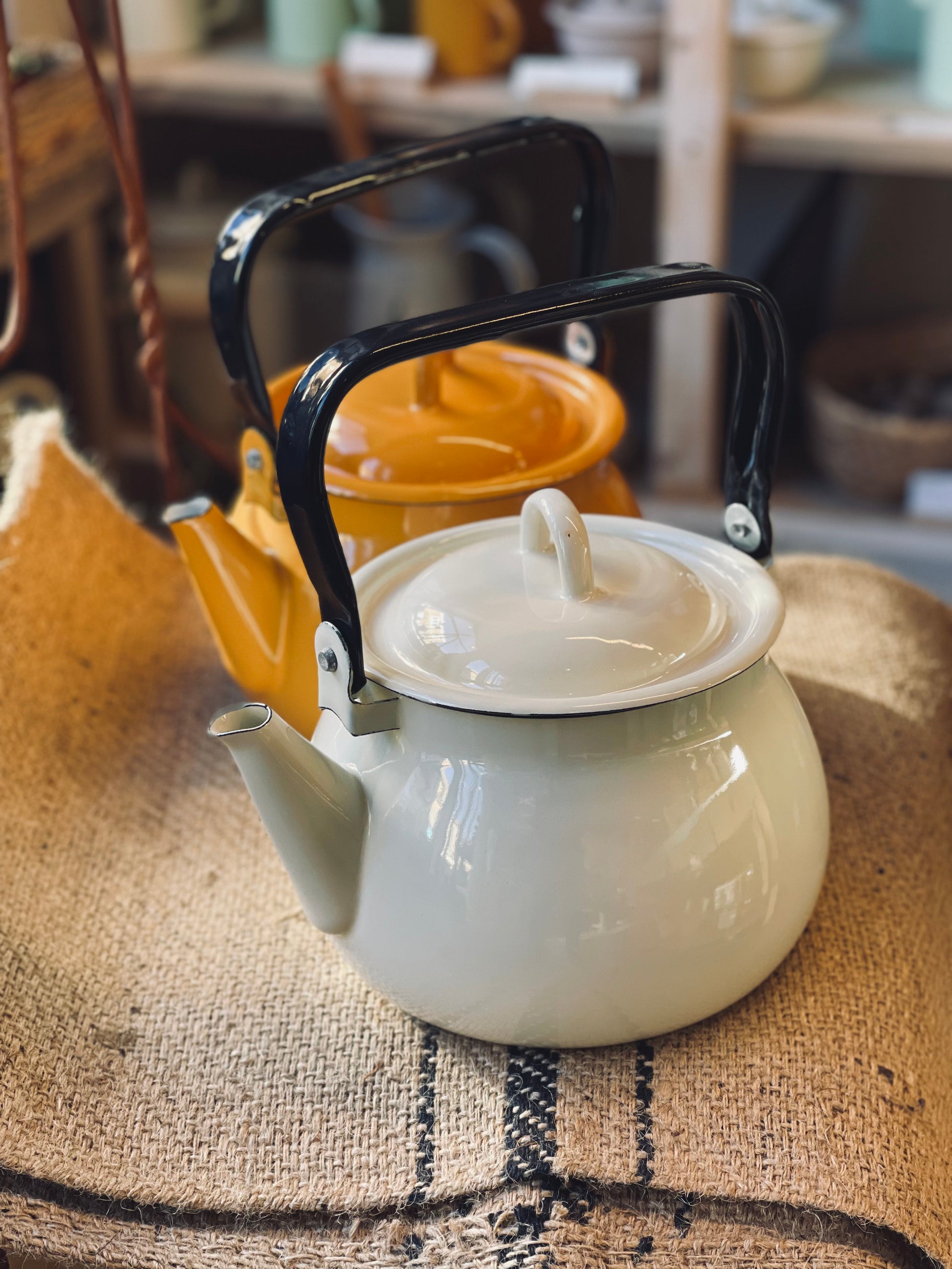 Cream kettle with black handle on a textured surface