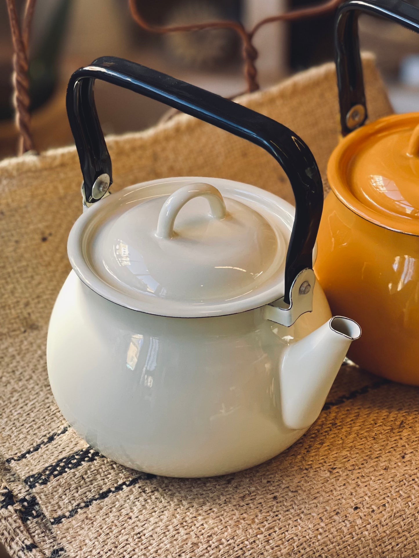 Cream White kettle with black handle on a textured surface