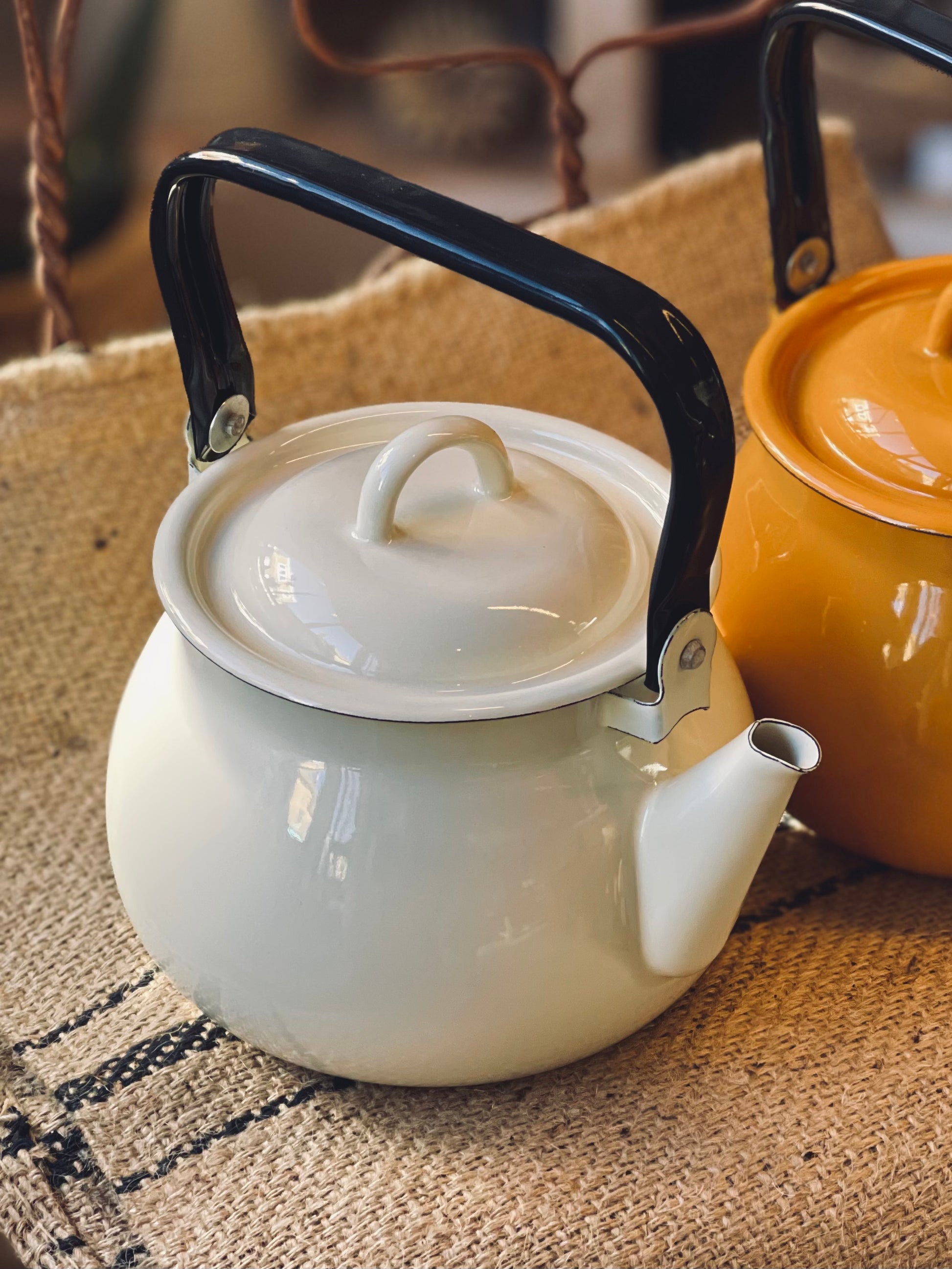 Cream White kettle with black handle on a textured surface