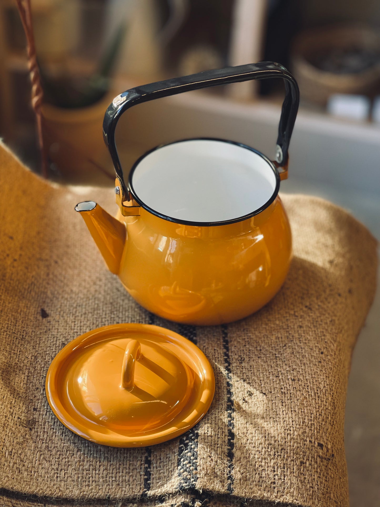 Yellow kettle with black handle on a textured surface
