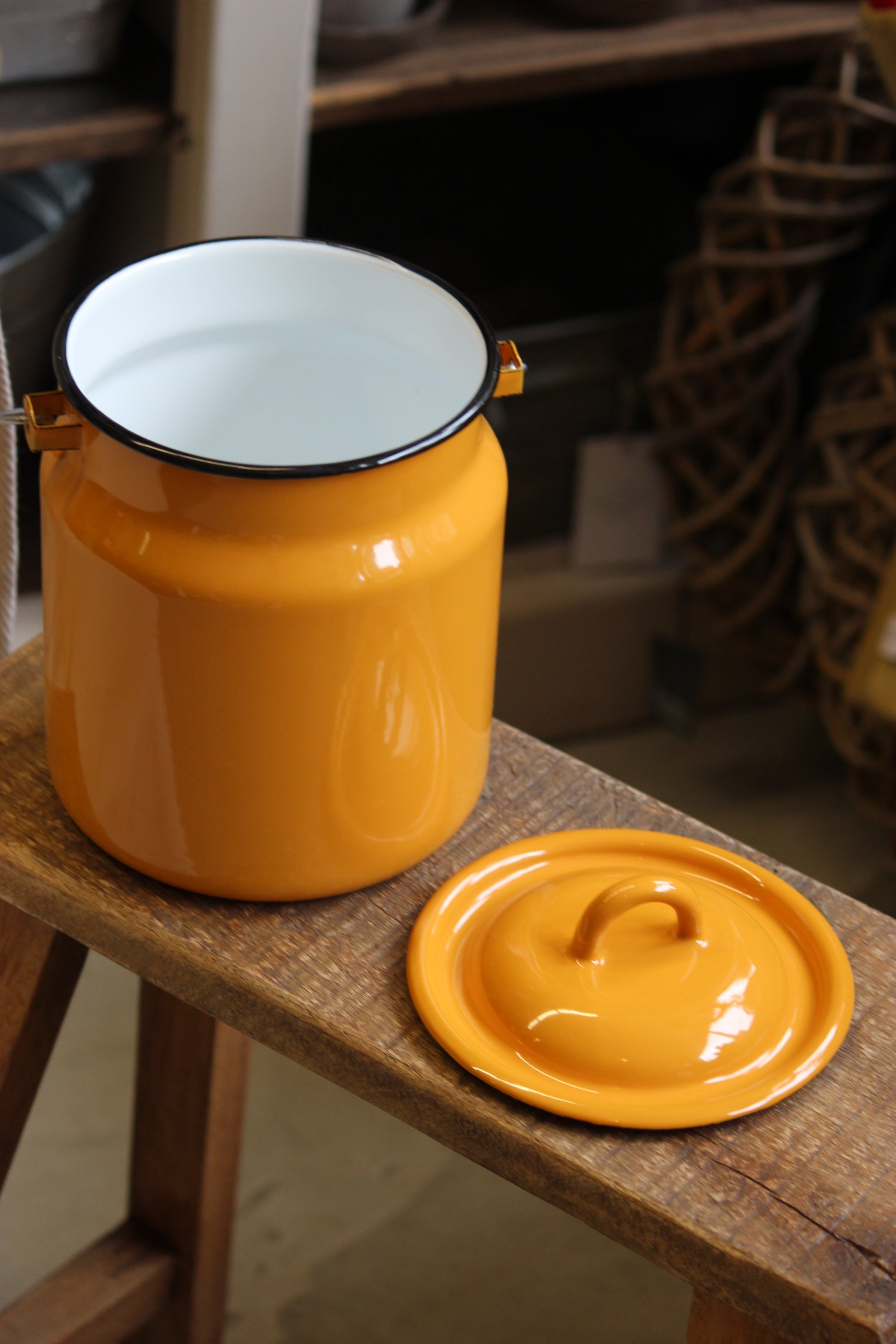 Yellow enamel jar with white interior on a wooden surface