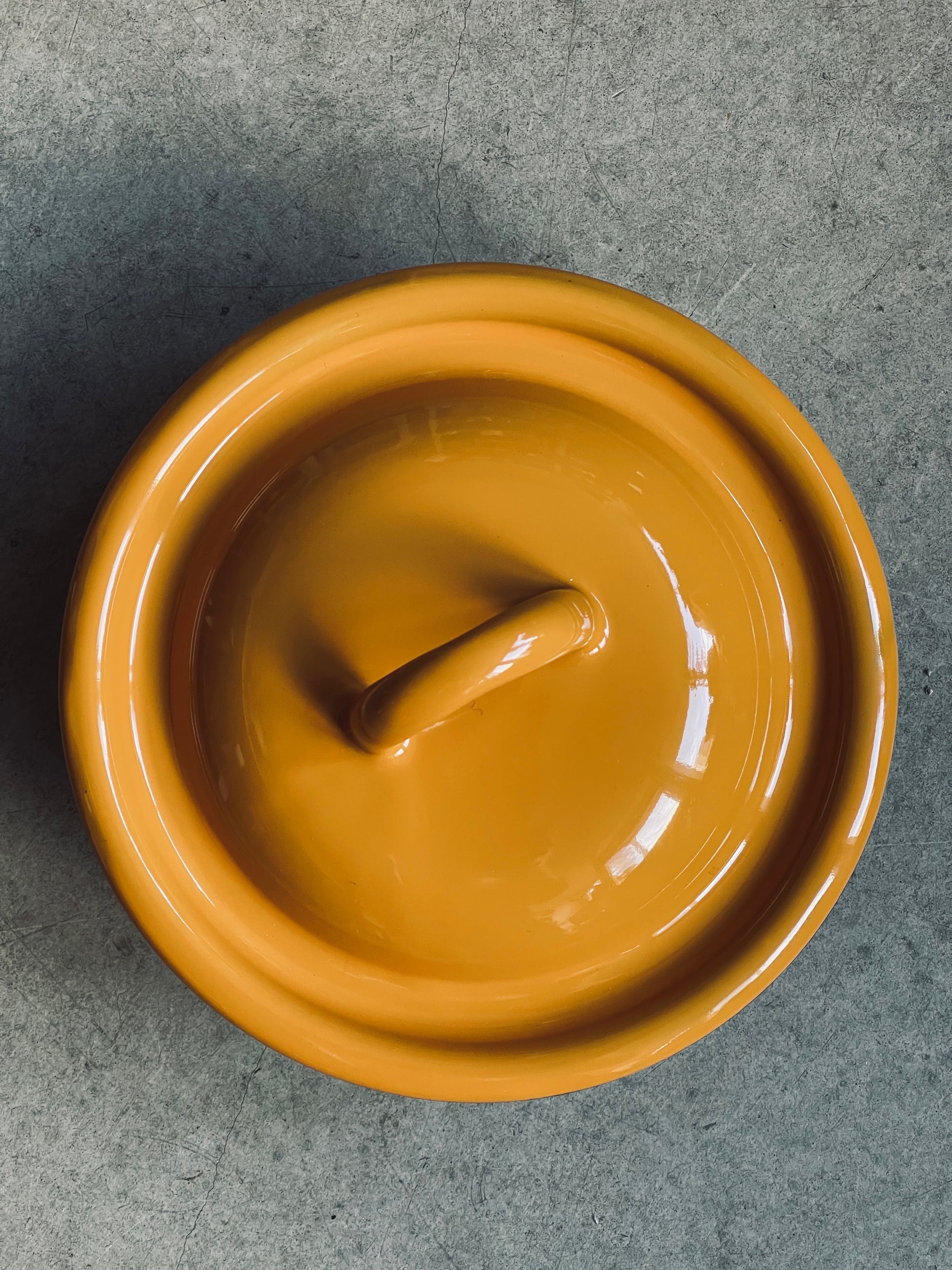 Ukrainian made Mustard yellow enamel pot with a lid on a gray surface