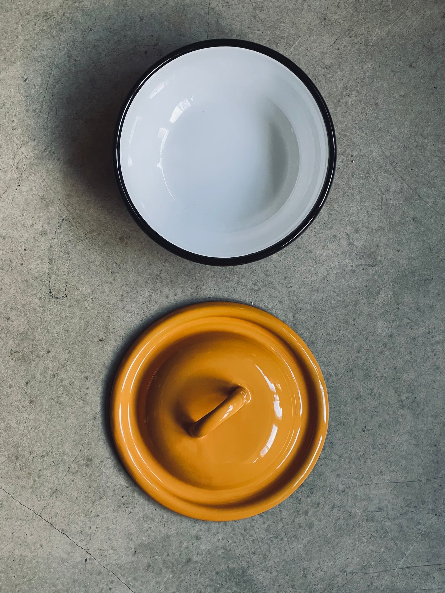 Ukrainian made enamel bowl with lid, on a gray surface.
