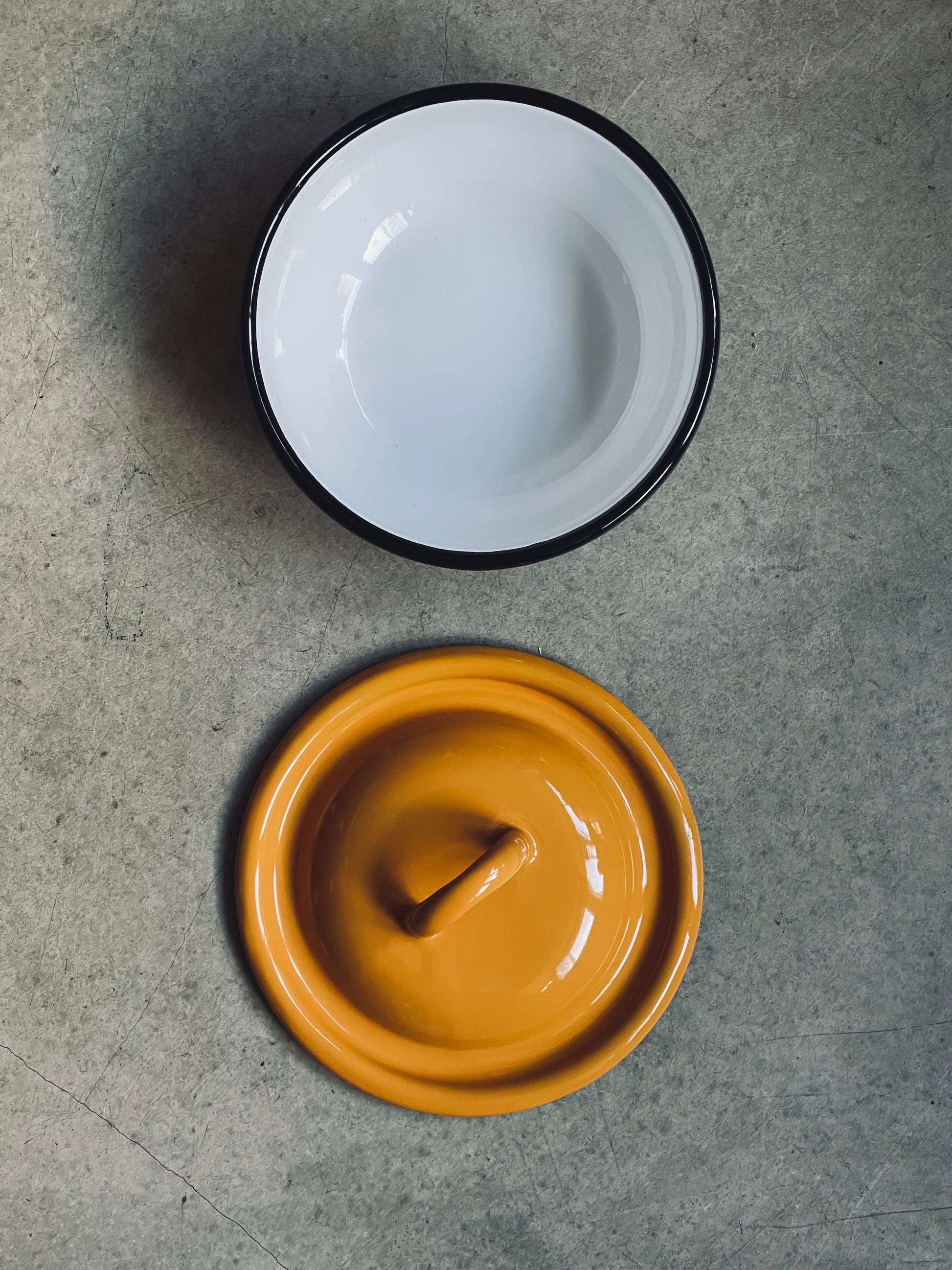 Ukrainian made enamel bowl with lid, on a gray surface.