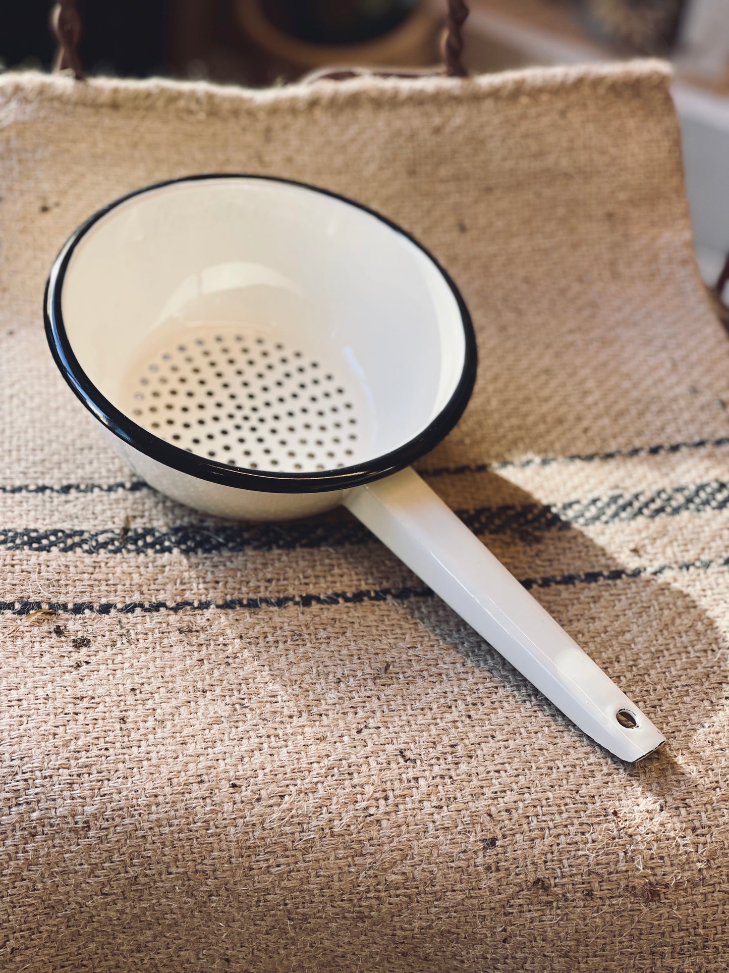 White colander with black rim on a textured fabric surface