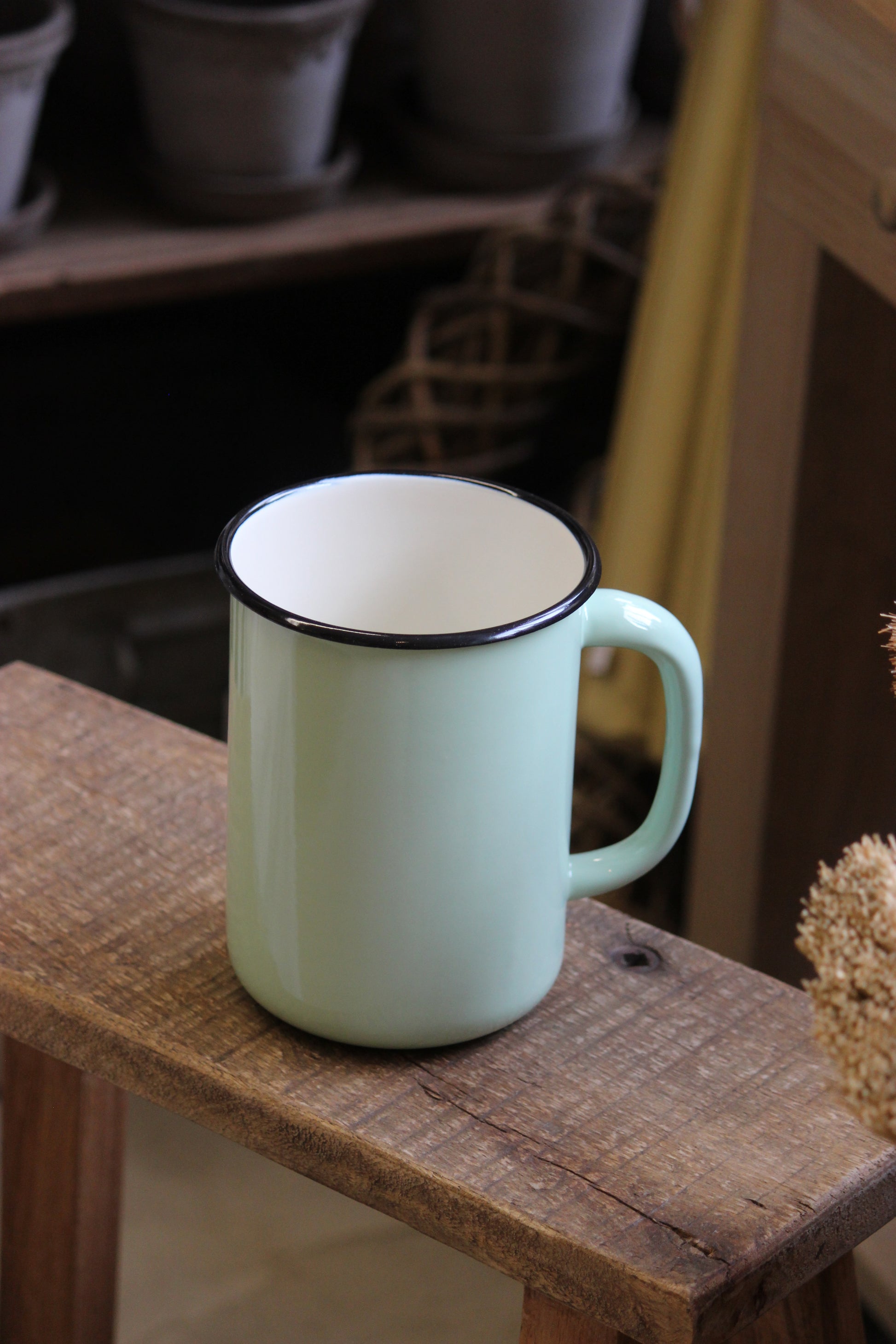 Light green jug with a black rim on a wooden surface