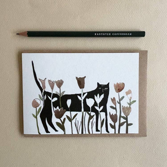 Card with black cat and flowers design on a beige background with a pencil.