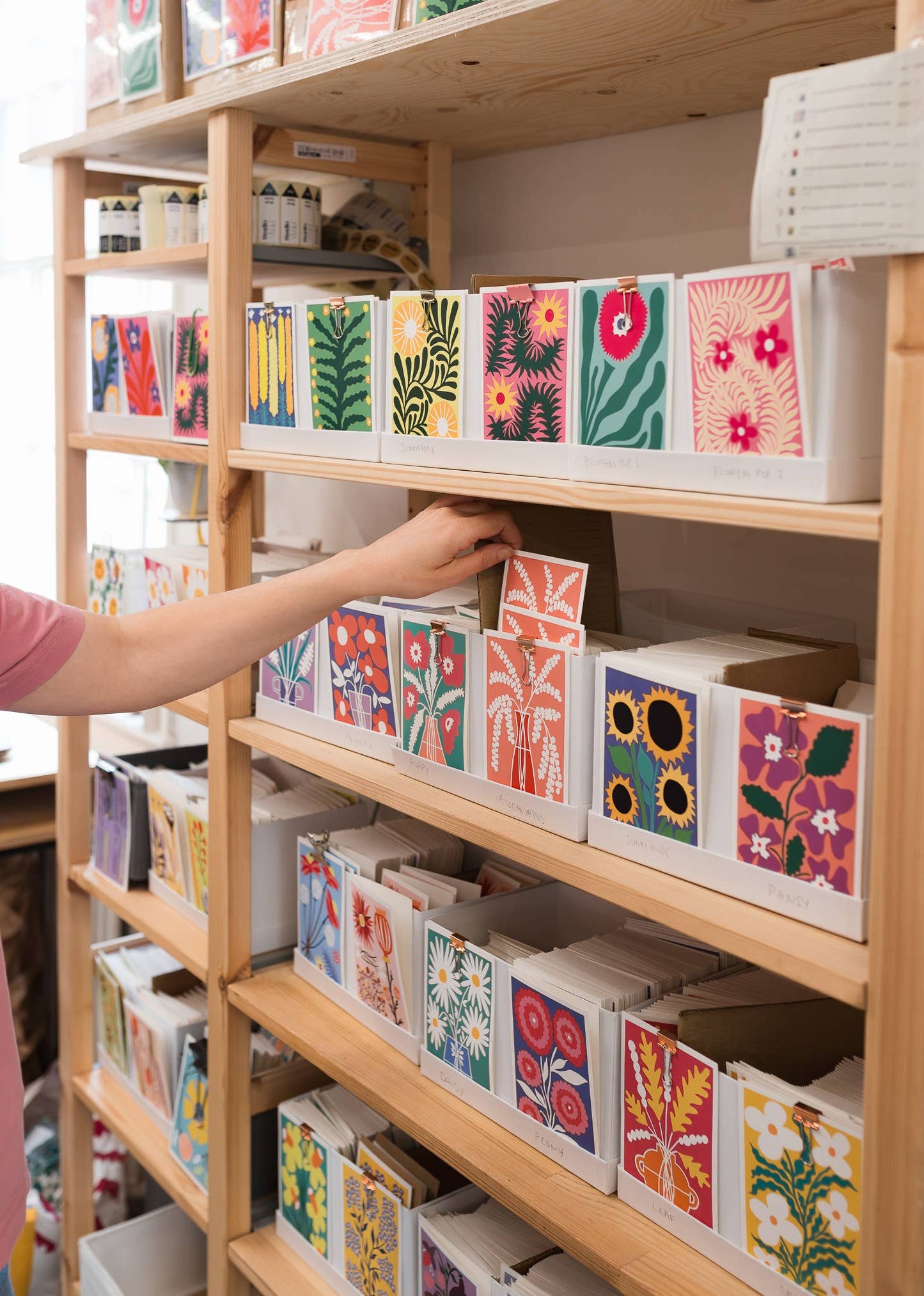 Shelf with colorful boxes and a hand reaching out to select one.