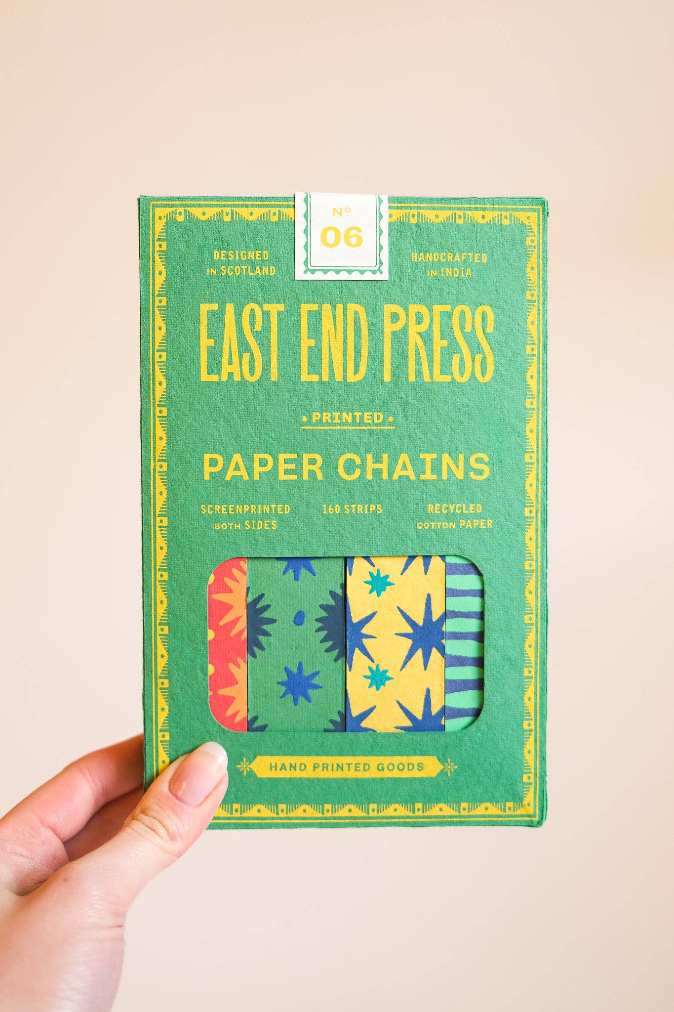 Pack of East End Press Celebration paper chains held by a hand on a beige background