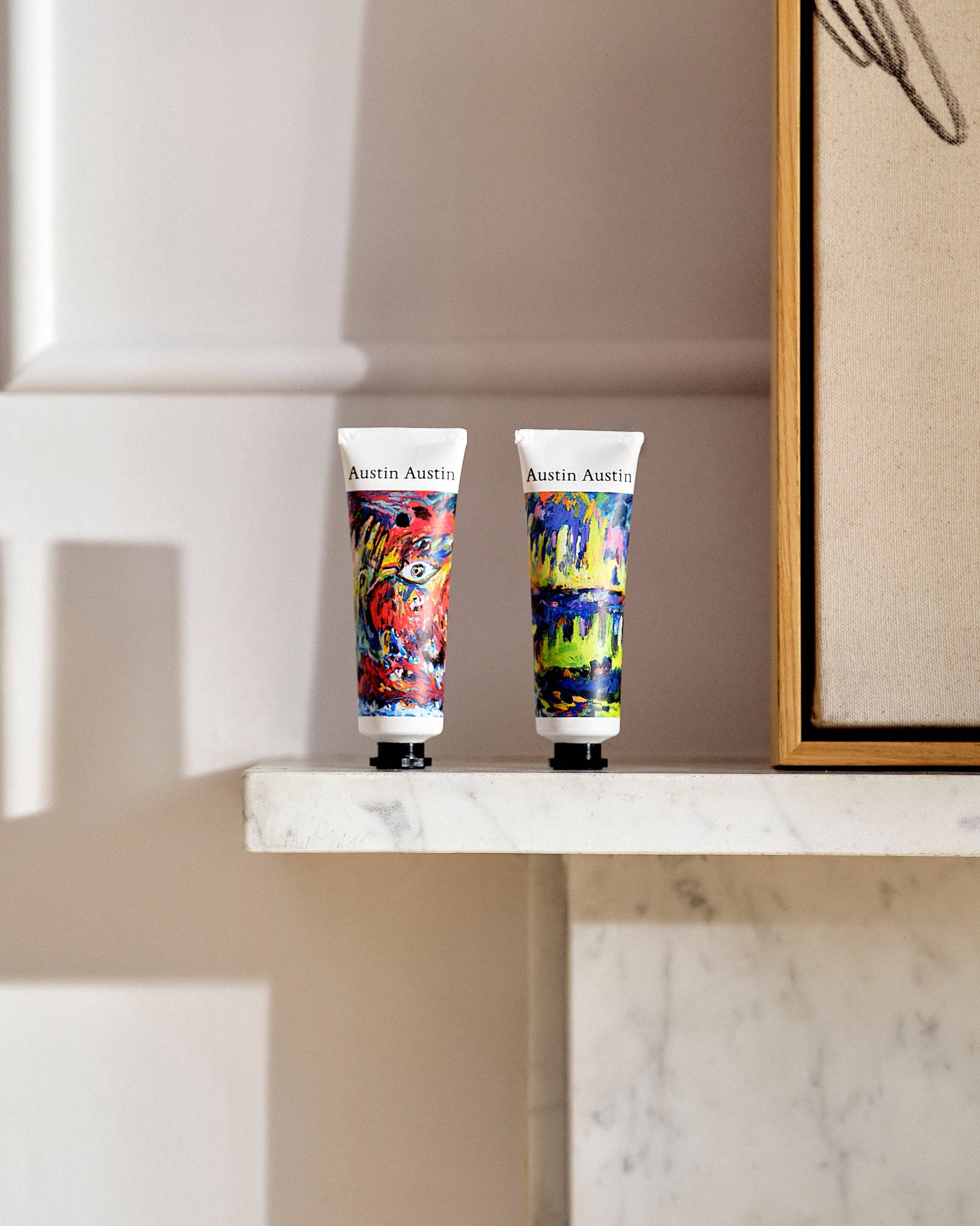 Two colourful Austin Austin hand cream tubes on a marble surface with a neutral background