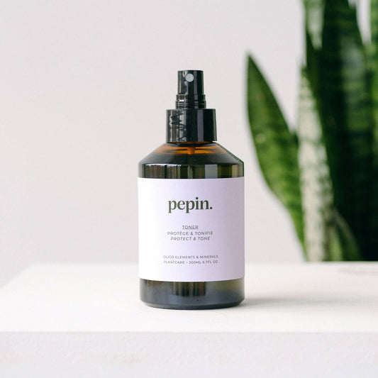 Bottle of 'pepin.' toner on a white surface with a plant in the background