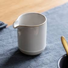 White ceramic pitcher on a blue cloth with a wooden surface in the background