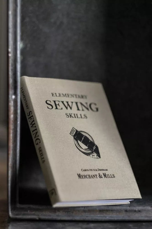 Book titled 'Elementary Sewing Skills' by Merchant & Mills on a dark background