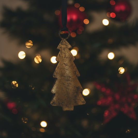 Decorative Christmas tree ornament hanging against a warm, blurred background with lights.