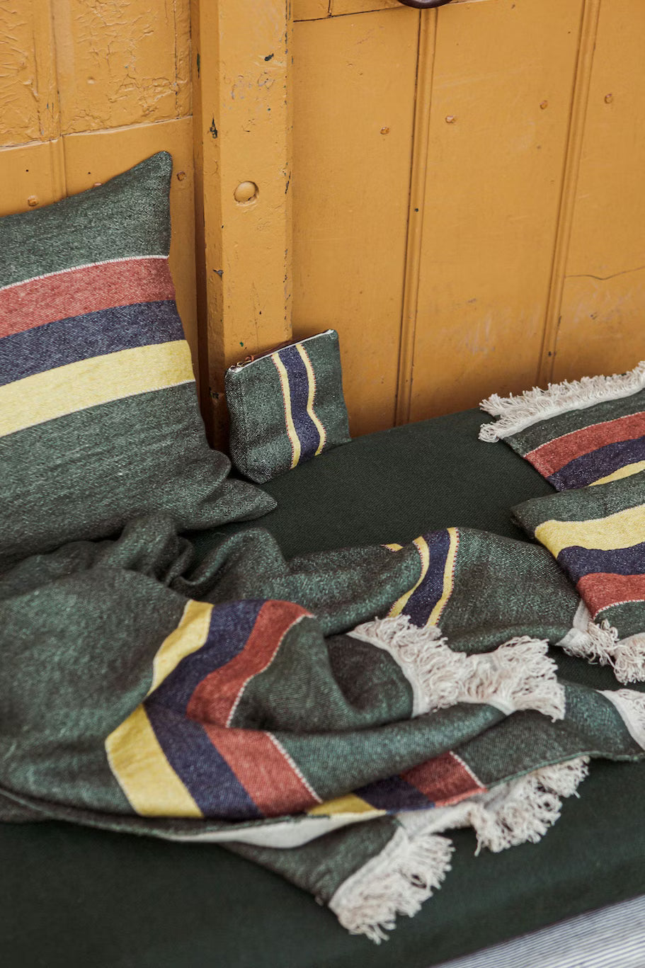 Striped cushions and blanket on a wooden bench